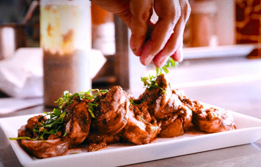 A dish being finished with fresh coriander in the Café Spice Namasté kitchen